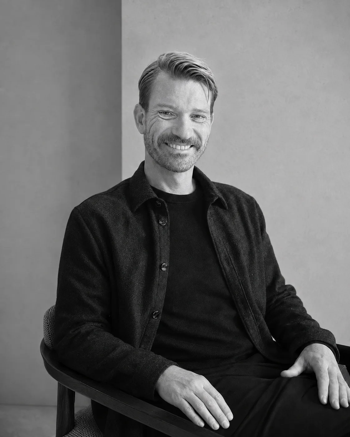 Jacob Top Møller seated in a chair, wearing a dark open overshirt; black-and-white portrait